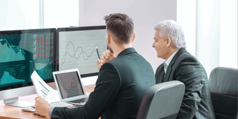 Deux hommes analysent des graphiques financiers.